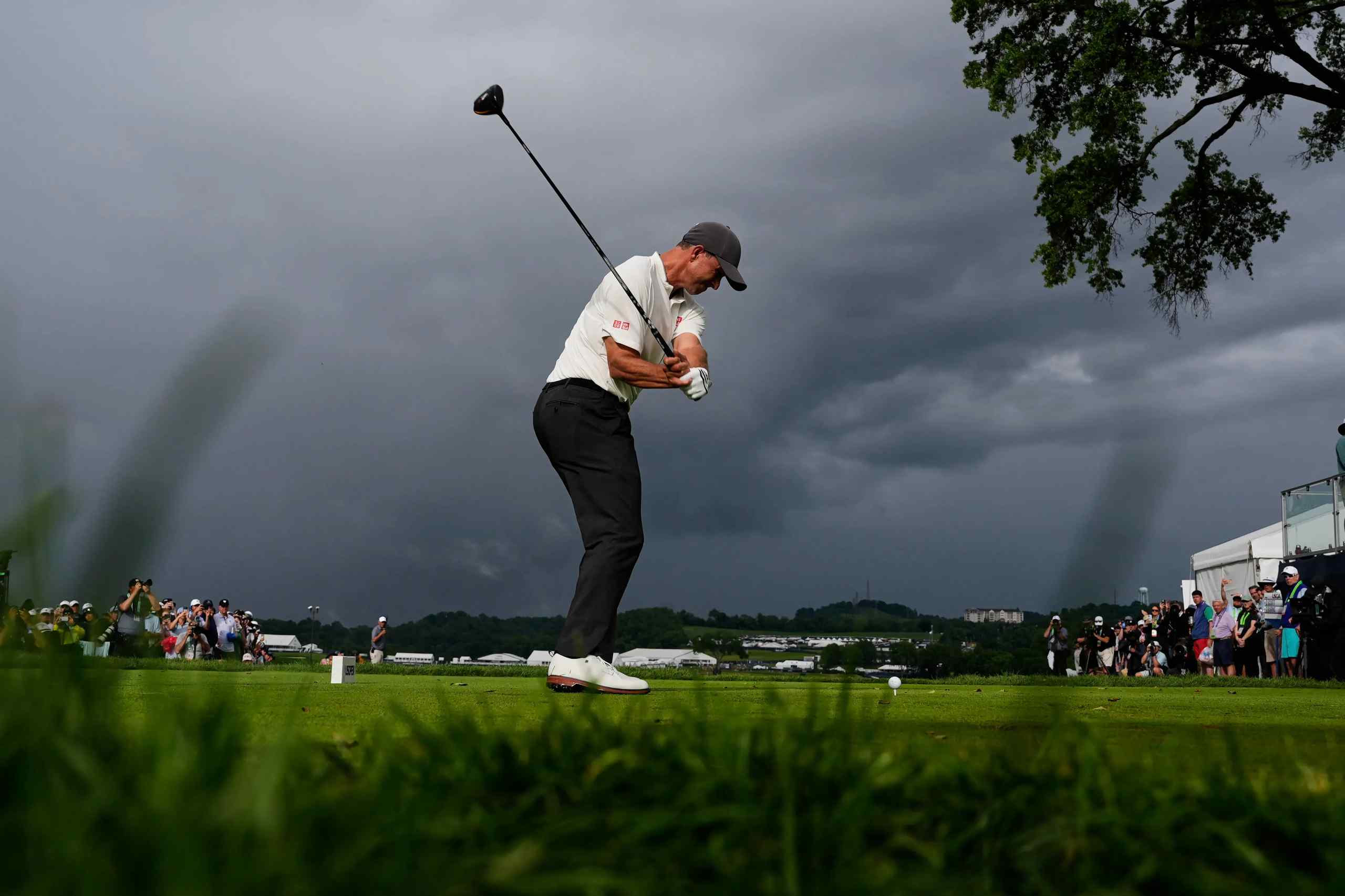 A man golfing amidst a cloudy sky.